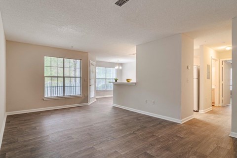 A spacious room with wooden flooring and a large window.