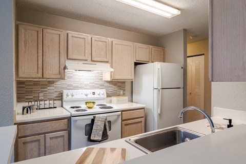 A kitchen with a white stove top oven and a white refrigerator.