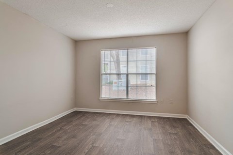 A room with a window and wooden flooring.