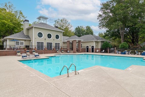 A swimming pool in front of a house with a pool house.