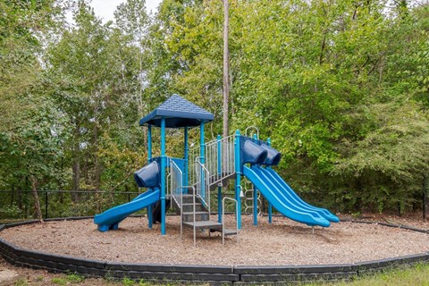 A playground with a blue slide and a blue roofed structure.