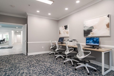 A room with a desk and chairs and a painting on the wall.