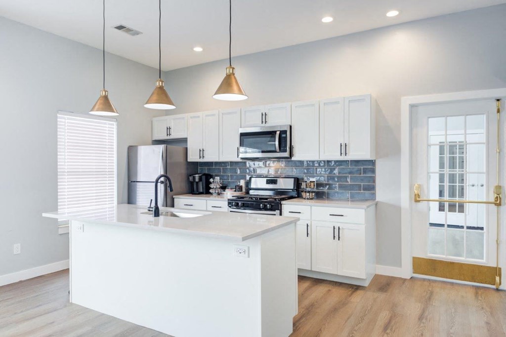 A kitchen with white cabinets and a white island.