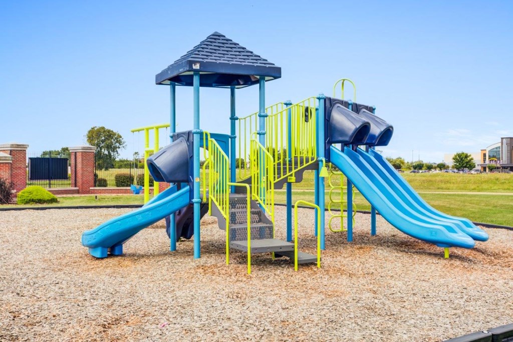 A playground with a blue slide and yellow safety barriers.