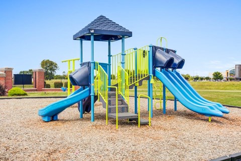 A playground with a blue slide and yellow safety barriers.