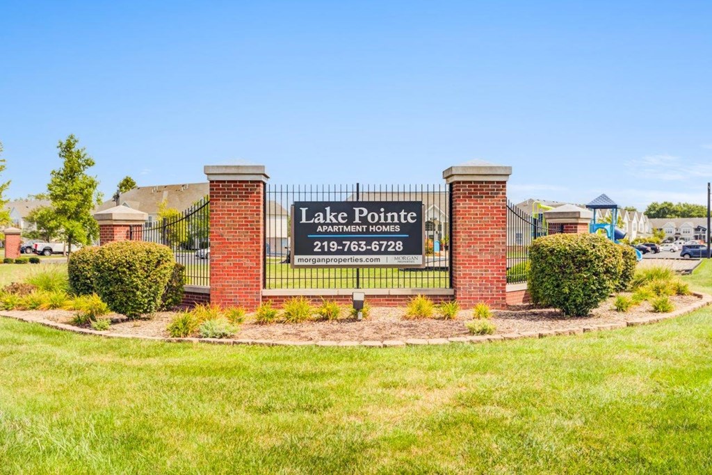A sign for Lake Pointe Apartment Homes is displayed in front of a grassy area.