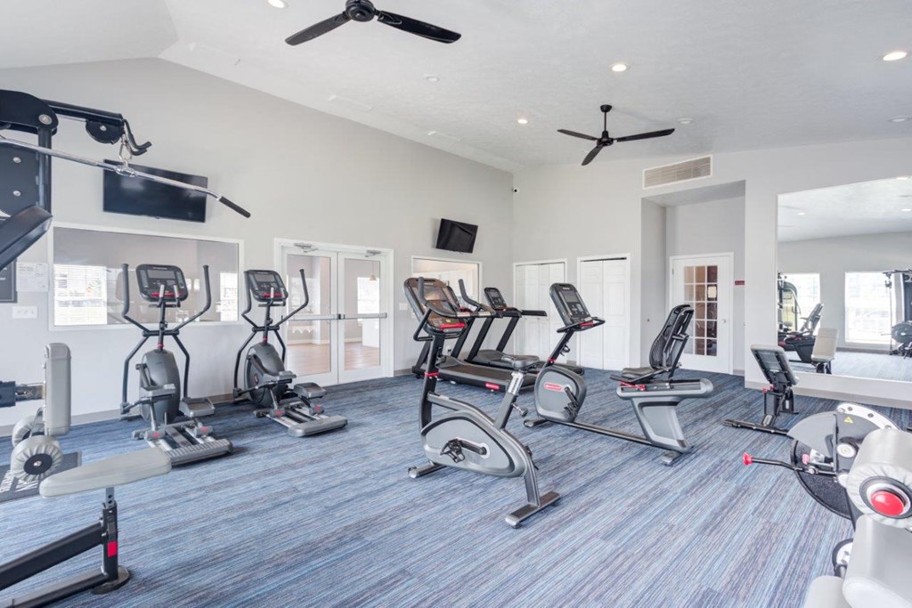 A gym with a variety of exercise equipment including treadmills, stationary bikes, and weight machines.