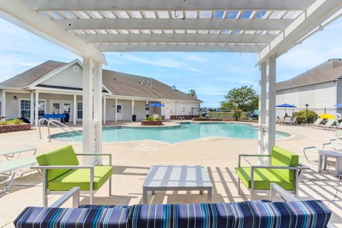 A pool area with a white pergola and a striped bench.