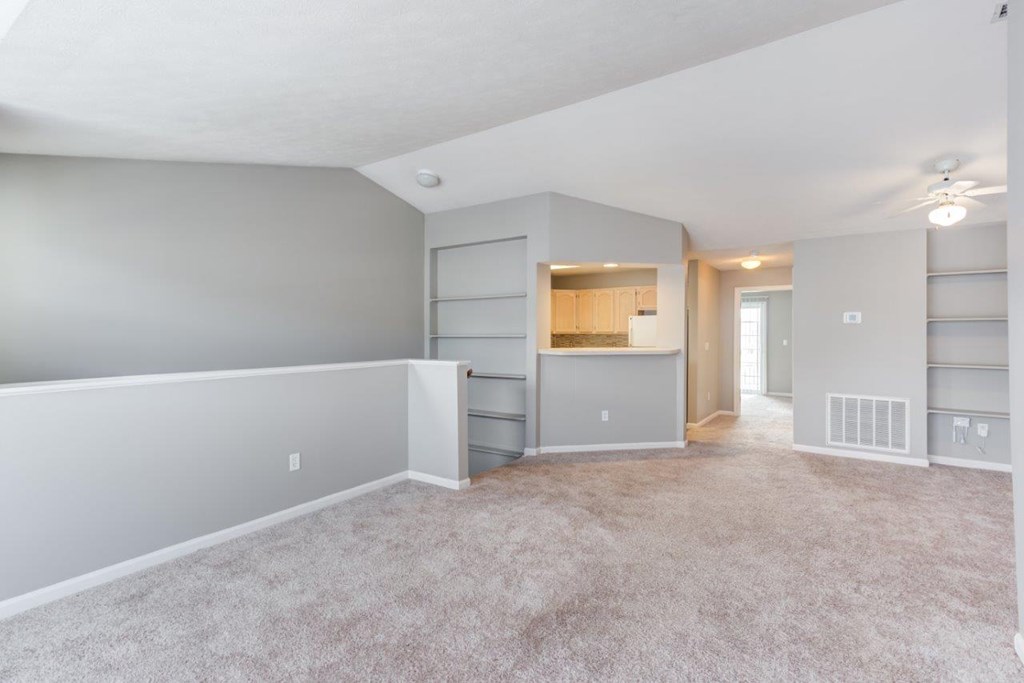 A spacious living room with a kitchenette in the background.
