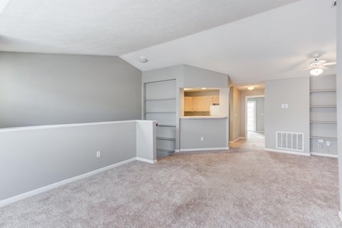 A spacious living room with a kitchenette in the background.