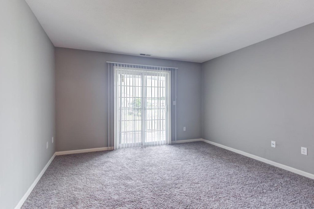 A room with grey walls and a carpeted floor with a sliding glass door.