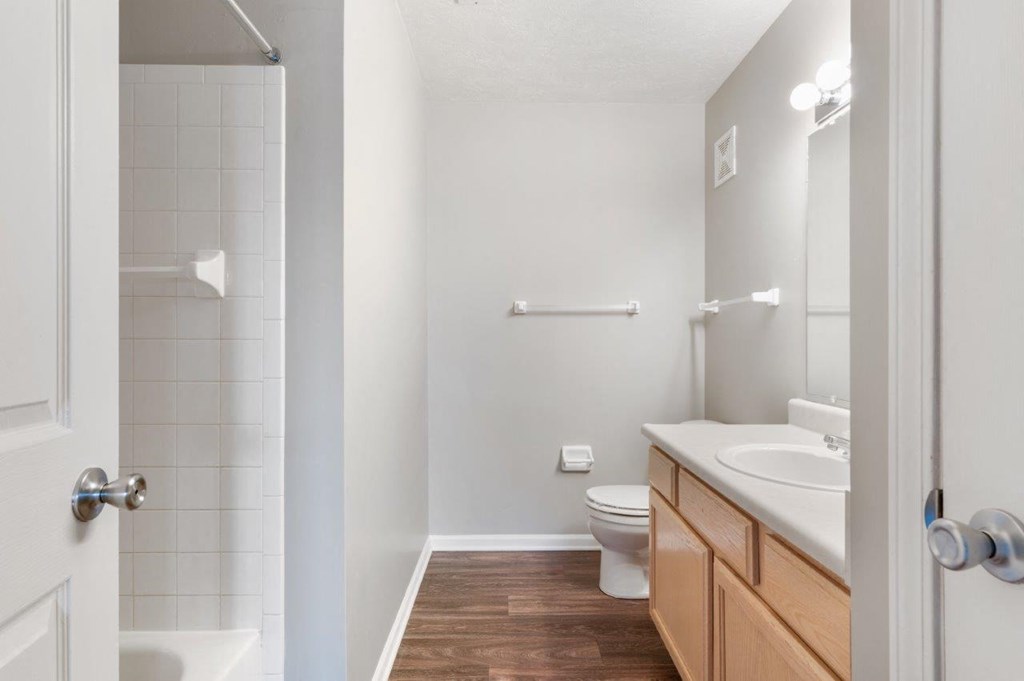 A white bathroom with a toilet, sink, and a walk-in shower.