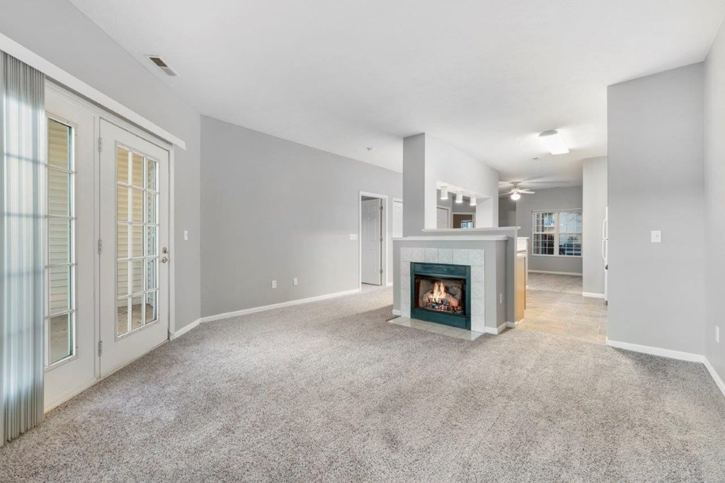 A living room with a fireplace and grey carpet.
