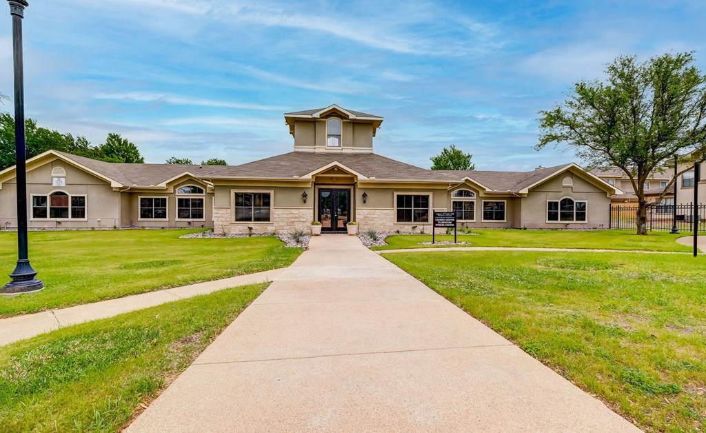 the front of a building with a sidewalk and grass