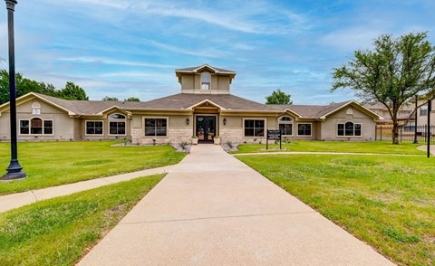 the front of a building with a sidewalk and grass