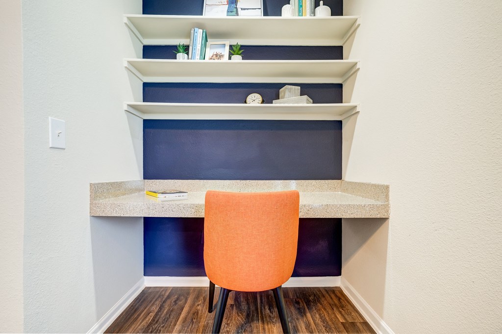 an office with a desk and a chair in front of a blue wall