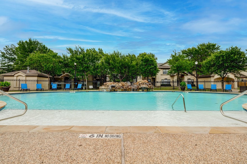 a swimming pool with trees and apartments in the background
