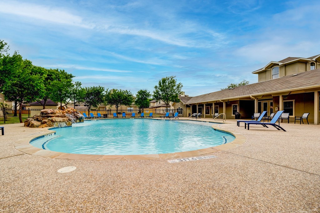 our resort style swimming pool is surrounded by chairs and a building