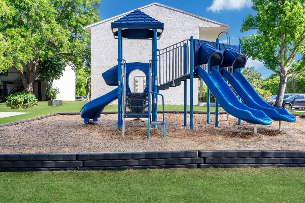 a playground with a blue swing set in front of a house