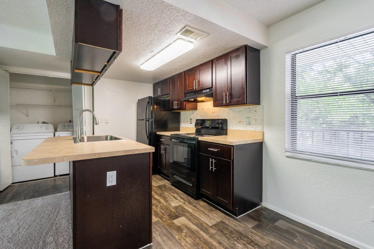 a kitchen with dark wood cabinets and a large window