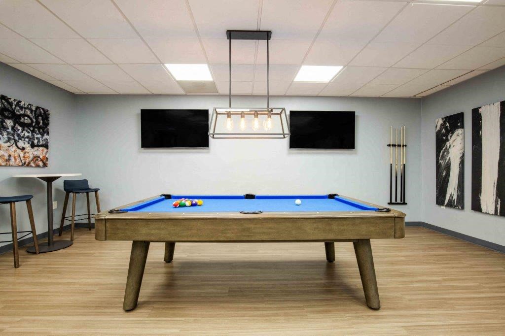 a games room with a pool table and televisions