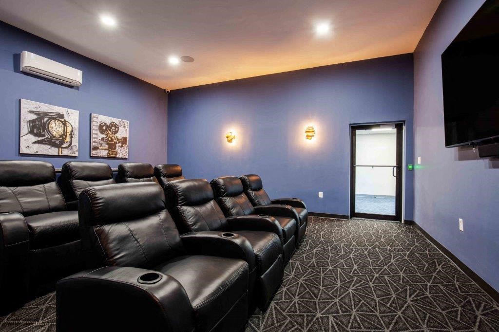 a home theater room with blue walls and leather chairs