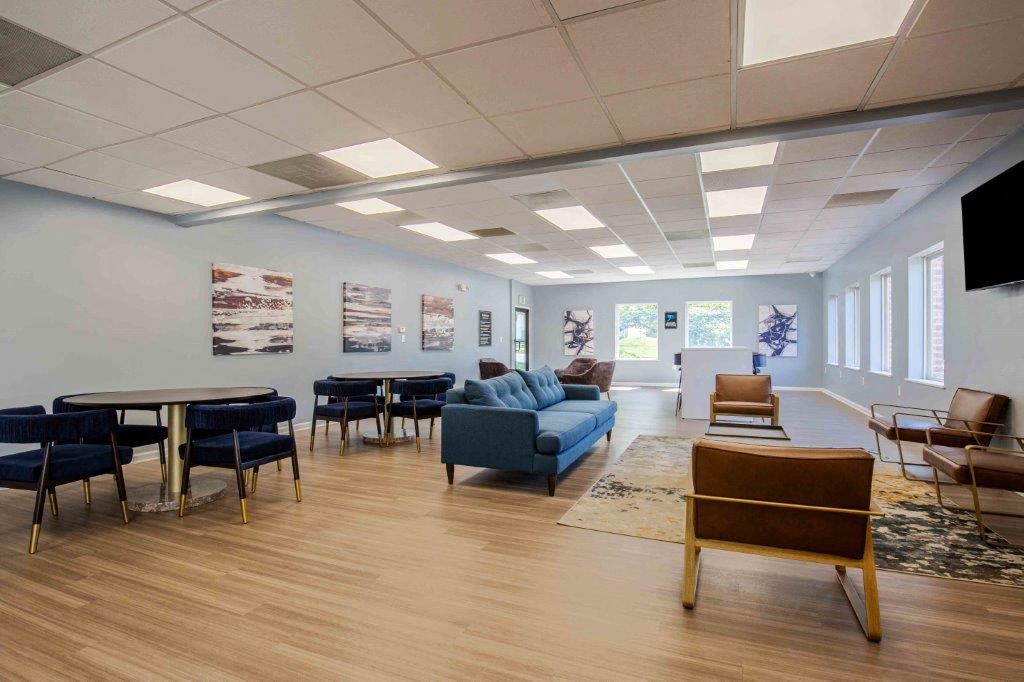 a waiting room with couches chairs and tables and a tv