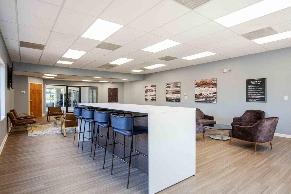 a lobby with a bar with blue stools and chairs