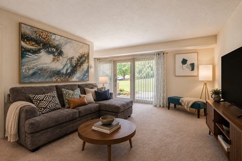 A living room with a grey couch, a coffee table, and a painting on the wall.