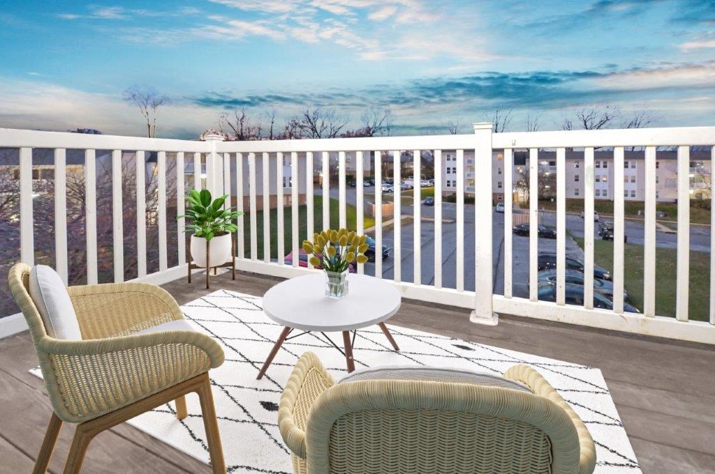 a patio with chairs and a table on a balcony overlooking the ocean