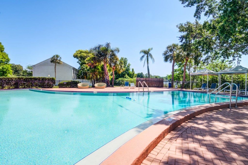 a swimming pool with trees and a building in the background