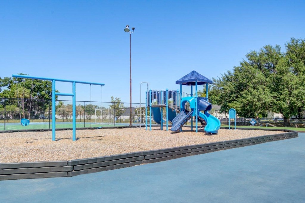 a playground with a blue playset and a swing set