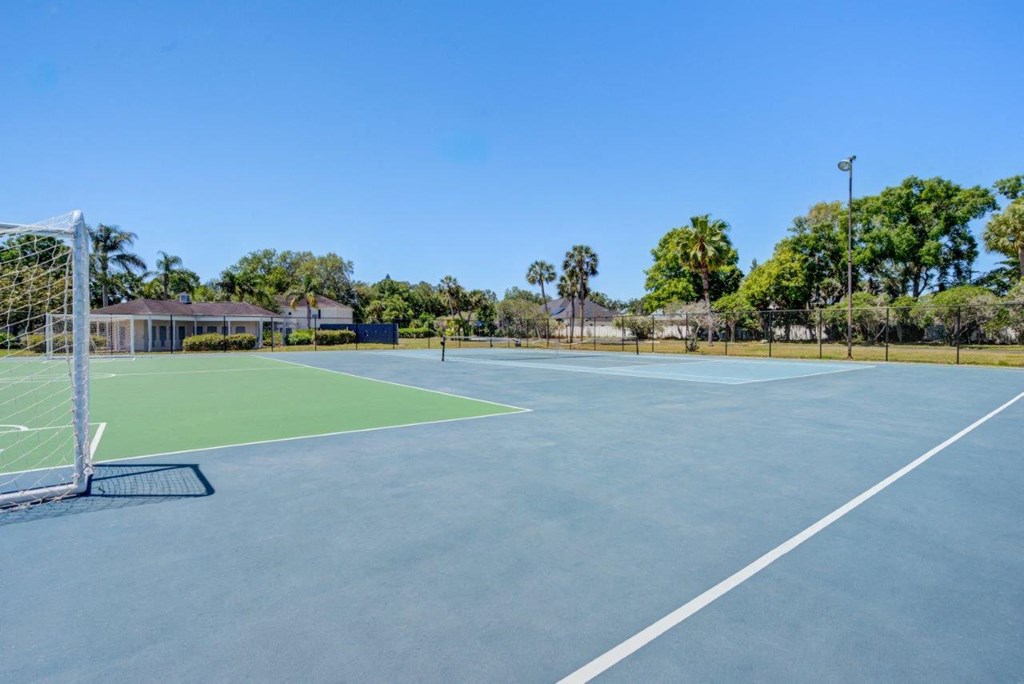 a tennis court with trees in the background on a clear day