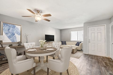 a living room and dining room with white furniture and a ceiling fan