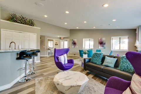 A living room with a purple chair and a black couch.