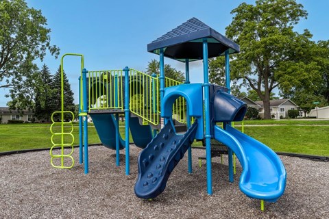A playground with a blue slide and yellow handrails.