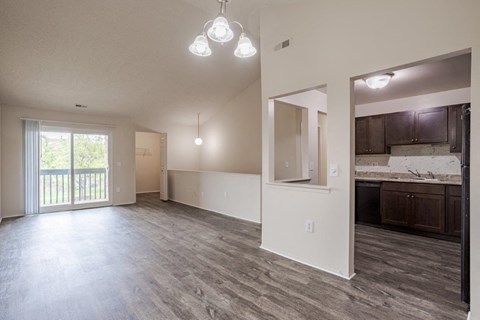 A spacious room with wooden flooring and a large window.