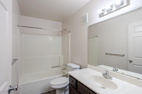 A white bathroom with a toilet, sink, and mirror.