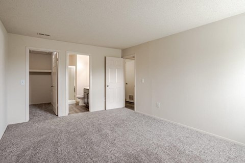 A large empty room with carpeted floor and white walls.