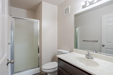 A white sink in a bathroom with a toilet and a glass door.