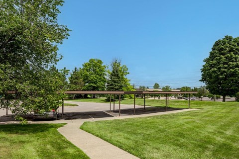 A green lawn with a pathway leading to a covered area.