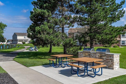 A picnic table with a stone pillar and a tree in the background.
