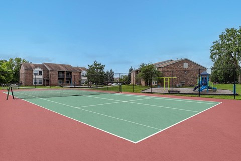 A tennis court with a red surface and green boundary lines.