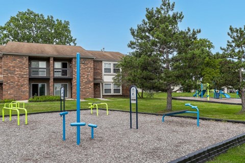 A playground with a blue and yellow structure in front of a brick building.