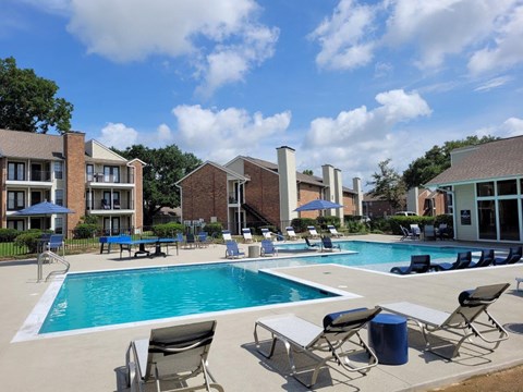 A swimming pool surrounded by chairs and buildings.