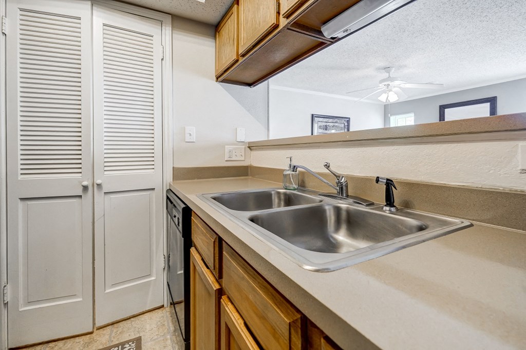 the kitchen has a stainless steel sink and wooden cabinets