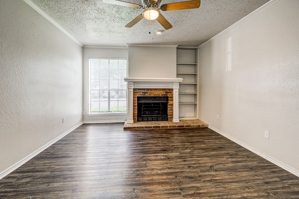 an empty living room with a fireplace and a ceiling fan
