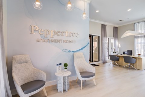 A modern living room with a Peppertree Apartment Homes sign on the wall.