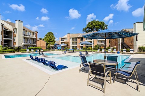 A pool area with chairs and a table.