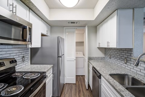 A kitchen with a stove, refrigerator, and sink.